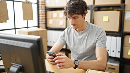 Young hispanic man ecommerce business worker using smartphone at office