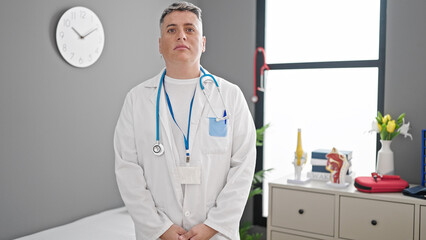 Young caucasian man doctor standing with serious expression at the clinic