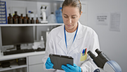 Focused young blonde woman scientist engrossed in her groundbreaking biology experiment, using a...