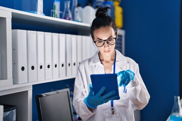 Young caucasian woman scientist using touchpad at laboratory