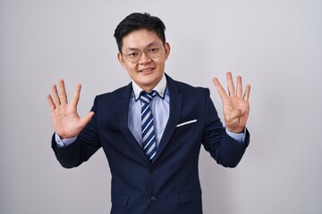 Young asian man wearing business suit and tie showing and pointing up with fingers number nine while smiling confident and happy.