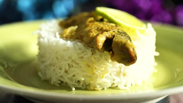 Nicely decorated platter lunch with fish, rice and lemon slices served in a yellow plate on a wooden table. Indian dish for lunch and dinner.
