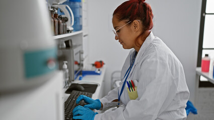 Focused young irish redhead woman scientist concentrating on her computer work in medicine research lab