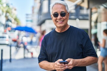 Middle age grey-haired man smiling confident using smartphone at street