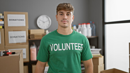 Handsome young hispanic man volunteers at charity center, his serious face reflecting the gravity...