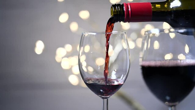 Pouring glass of red wine from a bottle. Close up female hand pouring red wine to glass. Sommelier tasting, rating and drinking wine. Restaurant, wine bar, waitress.