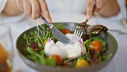 Young woman mixing burrata salad at the restaurant