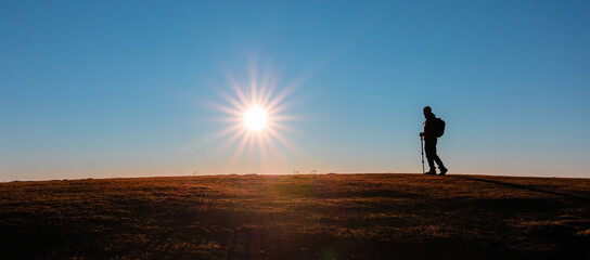 Silhouette of hiker against the sky at sunset