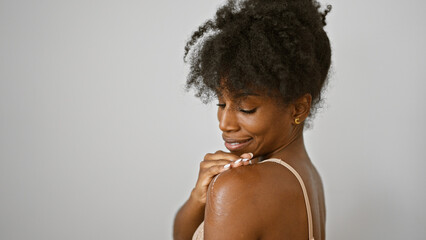African american woman wearing lingerie applying lotion skin treatment on shoulder smiling over...