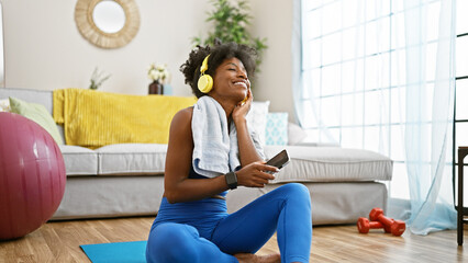 African american woman wearing sportswear listening to music dancing at home