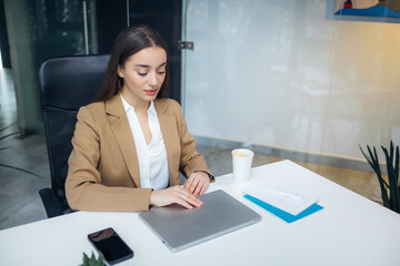 Happy business woman entrepreneur in office open laptop at work wearing suit working on computer at workplace.