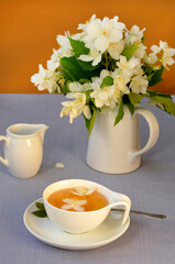 still life with a cup of tea and a bouquet of white jasmine flowers