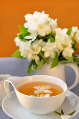 white cup of herbal tea with jasmine flowers close-up