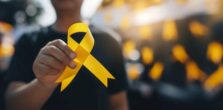 Man holding yellow ribbon. World cancer day, International Childhood Cancer Day, Cancer awareness concept. Suicide prevention day, Sarcoma, bone and bladder cancer Awareness month. For banner