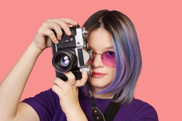 Teenager asian girl with old school photo camera against vibrant pink background. Youthful...