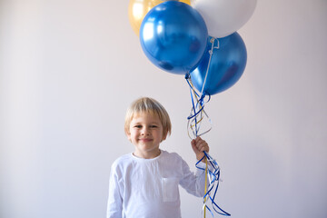 little blonde smiling boy holding balloons celebration birthday
