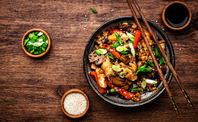 Stir fry turkey slices with red paprika, mushrooms, chives and sesame seeds with ginger, garlic and soy sauce. Old wooden table background, top view