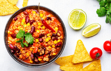 Chili con carne, mexican dish with minced beef, red beans, paprika, corn and hot peppers in spicy tomato sauce, tex-mex cuisine, white background, top view