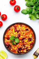 Chili con carne, mexican dish with minced beef, red beans, paprika, corn and hot peppers in spicy tomato sauce, tex-mex cuisine, white background, top view
