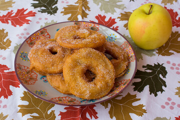 Buñuelos de manzana sobre mantel otoñal con hojas. Postre frito de manzana