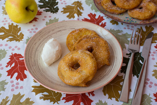 Bu&ntilde;uelos de manzana sobre mantel oto&ntilde;al con hojas. Postre frito de manzana