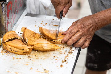 Vendor cutting delicious apam balik or peanut pancake into smaller pieces for sale