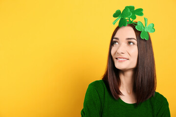 St. Patrick's day party. Pretty woman with green clover headband on golden background. Space for...