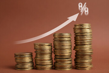 Mortgage rate. Stacked coins, arrow and percent sign on brown background