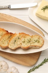 Tasty baguette with garlic and dill served on white wooden table, flat lay
