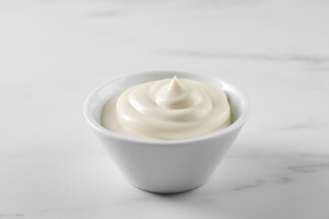 Tasty mayonnaise sauce in bowl on white table, closeup