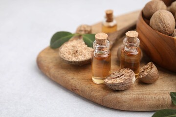 Nutmeg essential oil, nuts and leaves on light table. Space for text