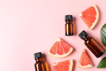 Flat lay composition with grapefruit essential oil on pink background. Space for text