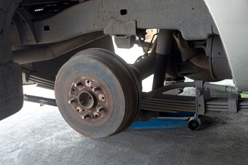 Close up of a car brake and a jack during car maintenance, car lifted on a jack.