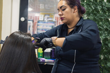 a woman straightening the hair of another Latin woman