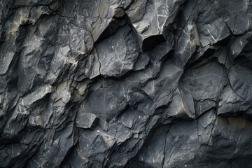 The jagged texture of this dark slate rock reflects a rugged history, etched by time and the elements, revealing nature's raw artistry. - obrazy, fototapety, plakaty