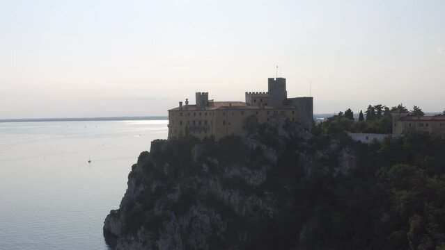 drone view of the silhouette duino's castle near to the sea in trieste on sunset