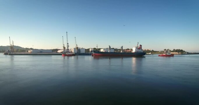 Big ship being towed to the harbour by tugboats