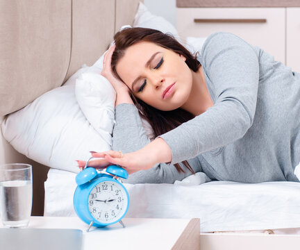 Young woman lying on the bed in time management concept