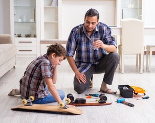 Young father repairing skateboard with his son at home