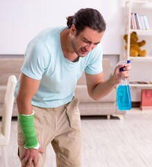 Obraz premium Young injured man cleaning the house