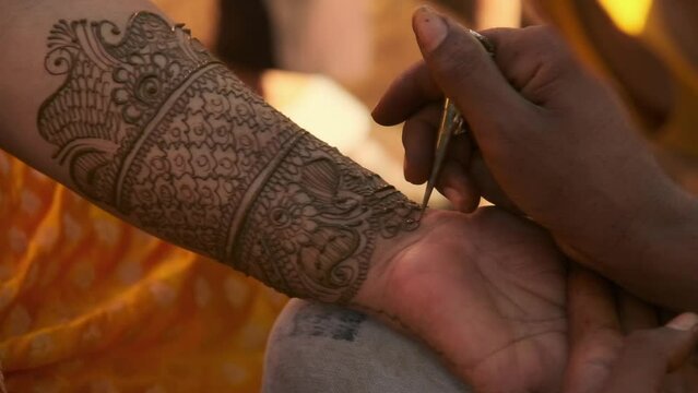 Close up handheld shot of Indian bride getting Henna design on her arm