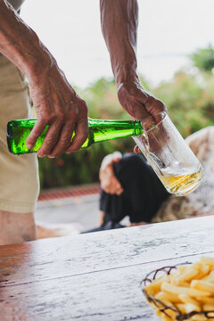 Hand of a man pouring beer from a bottle in a glass.