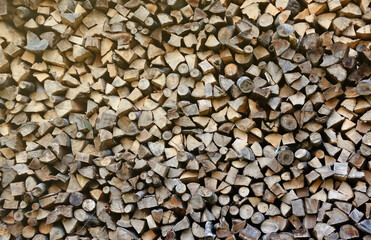 Firewood stacked near the wooden wall of old hut. Many chopped logs of firewood close up