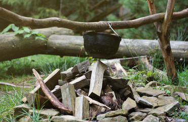 Tourist pot hanging over the fire on a tripod. Cooking in the campaign close up