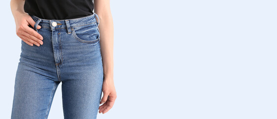 Young woman in stylish jeans on light background with space for text