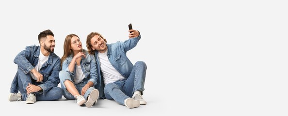 Stylish young people in jeans clothes taking selfie on white background with space for text