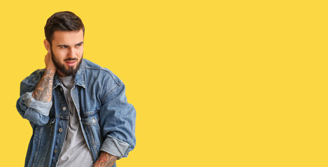 Stylish young man in jeans clothes on yellow background with space for text