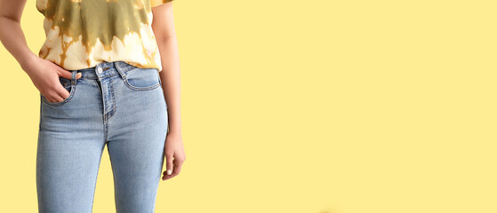 Naklejka premium Young woman in stylish jeans on yellow background with space for text