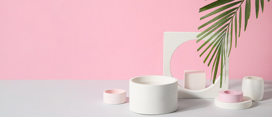 Plaster podiums and palm leaf on color background with space for text