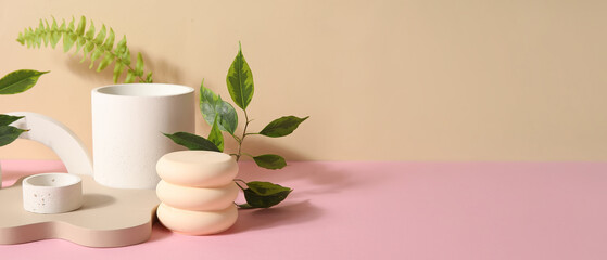 Plaster podiums and green leaves on color background with space for text